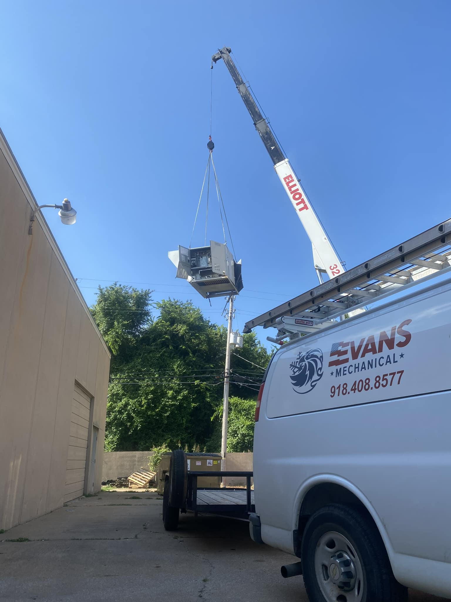 Evans Mechanical van on a commercial HVAC job site with crane